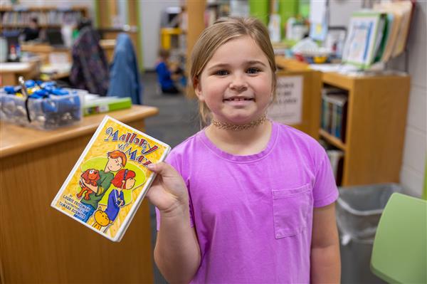 girl holding book and smiling
